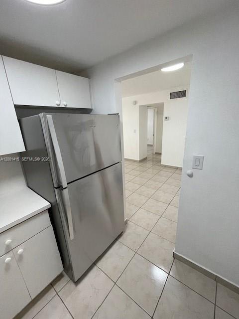 A stainless steel refrigerator stands in a kitchen with white cabinets and tiled floors — 606 W 81st St # 408, Hialeah FL 33014, HIALEAH, FL