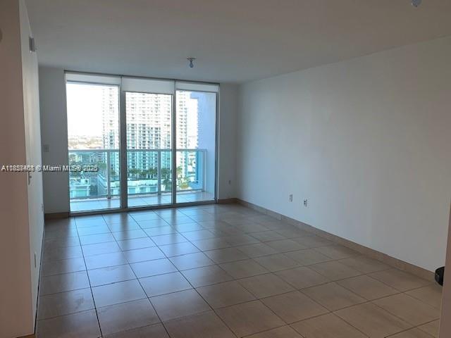 An empty room with light-colored tile flooring and floor-to-ceiling windows overlooking a city skyline — 31 SE 5th St # 2603, Miami FL 33131, MIAMI, FL