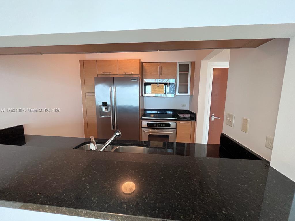 A kitchen features stainless steel appliances, light wood cabinets, and a black granite countertop — 31 SE 5th St # 2603, Miami FL 33131, MIAMI, FL