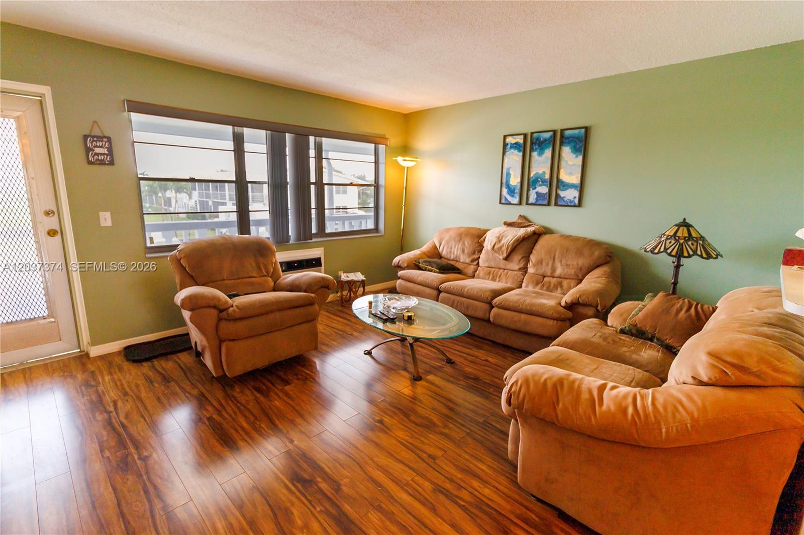 A living room features brown sofas, a glass coffee table, and wood-look flooring — 90 Berkshire D # 90, West Palm Beach FL 33417, WEST PALM BEACH, FL