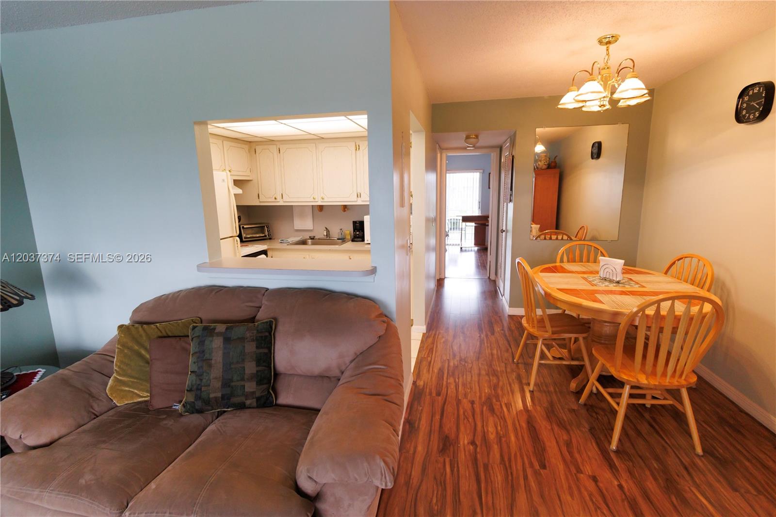 A living room with a brown sofa faces a kitchen pass-through and dining area — 90 Berkshire D # 90, West Palm Beach FL 33417, WEST PALM BEACH, FL