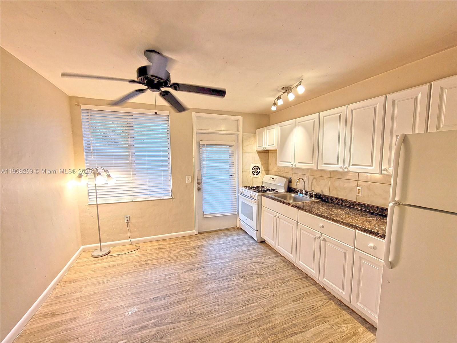 A kitchen features white cabinets, a dark countertop, a gas stove, and wood-look flooring — 441 Collins Ave # 12A, Miami Beach FL 33139, MIAMI BEACH, FL