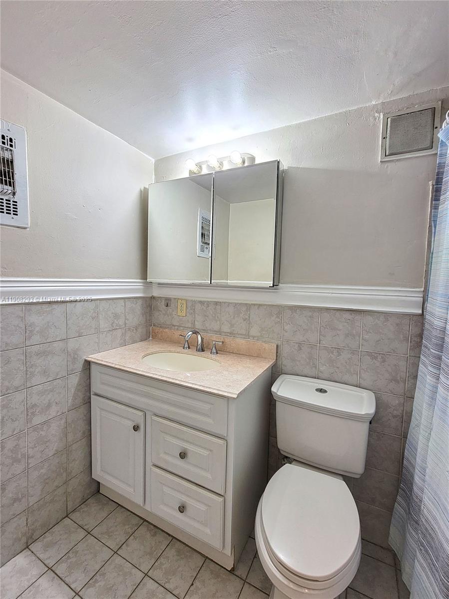 A bathroom features a vanity with a beige countertop, a medicine cabinet, and a toilet — 441 Collins Ave # 12A, Miami Beach FL 33139, MIAMI BEACH, FL