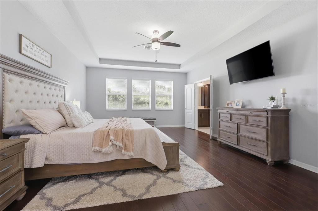 A bedroom features a tufted headboard, a wooden dresser, a ceiling fan, and hardwood floors — 297 ANCONA AVENUE, DEBARY, FL