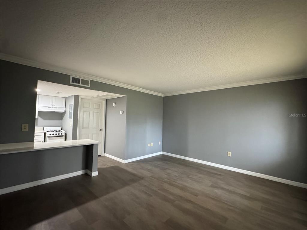 A living room with gray walls, wood-look flooring, and an open view into a kitchen — 120 BLUE POINT WAY UNIT 130, ALTAMONTE SPRINGS, FL
