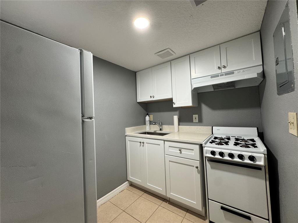 A small kitchen features white cabinets, a gas stove, a sink, and a refrigerator — 120 BLUE POINT WAY UNIT 130, ALTAMONTE SPRINGS, FL