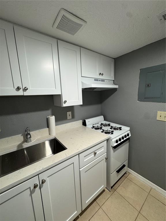 A kitchen features white cabinets, a stainless steel sink, and a white gas stove — 120 BLUE POINT WAY UNIT 130, ALTAMONTE SPRINGS, FL