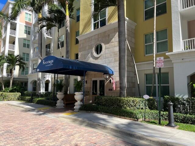 The exterior of a multi-story apartment building features a blue awning over the entrance — 806 E Windward Way # 401, Lantana FL 33462, LANTANA, FL