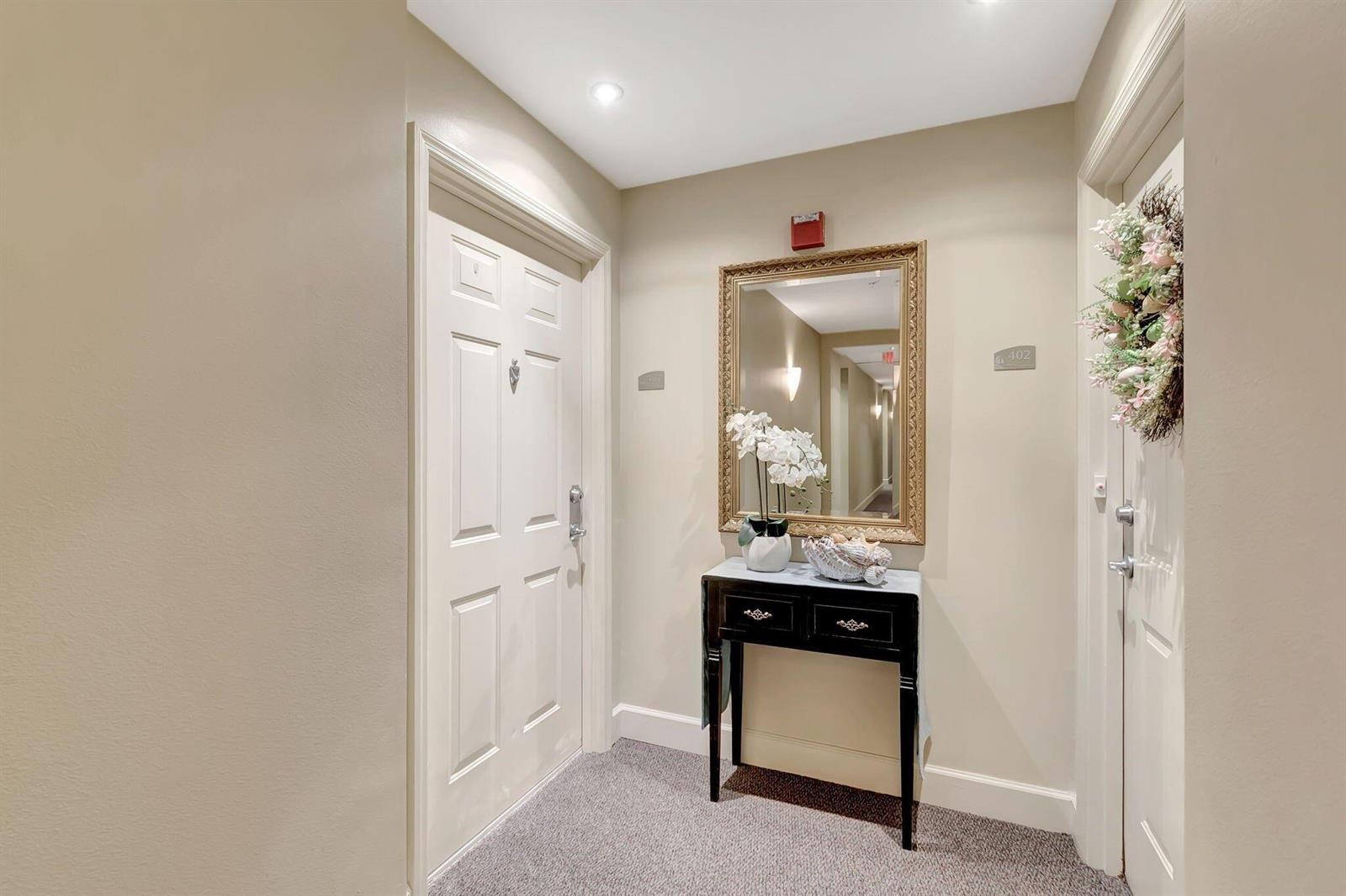 A small entryway features a white door, a console table with a mirror, and carpet — 806 E Windward Way # 401, Lantana FL 33462, LANTANA, FL