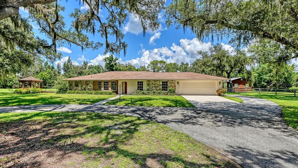 A single-story ranch house with a stone facade, attached garage, and a gazebo on the lawn — 6455 MCKOWN ROAD, SARASOTA, FL
