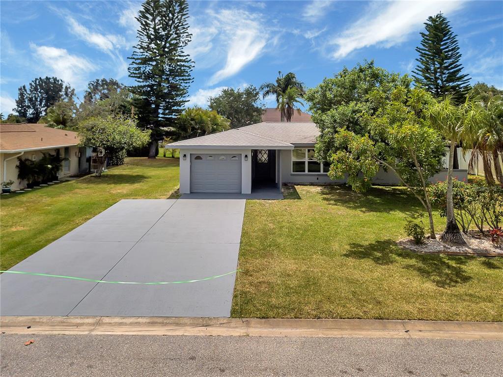 A single-story house with a gray garage, a concrete driveway, and a front lawn — 60 GOLFVIEW ROAD, ROTONDA WEST, FL