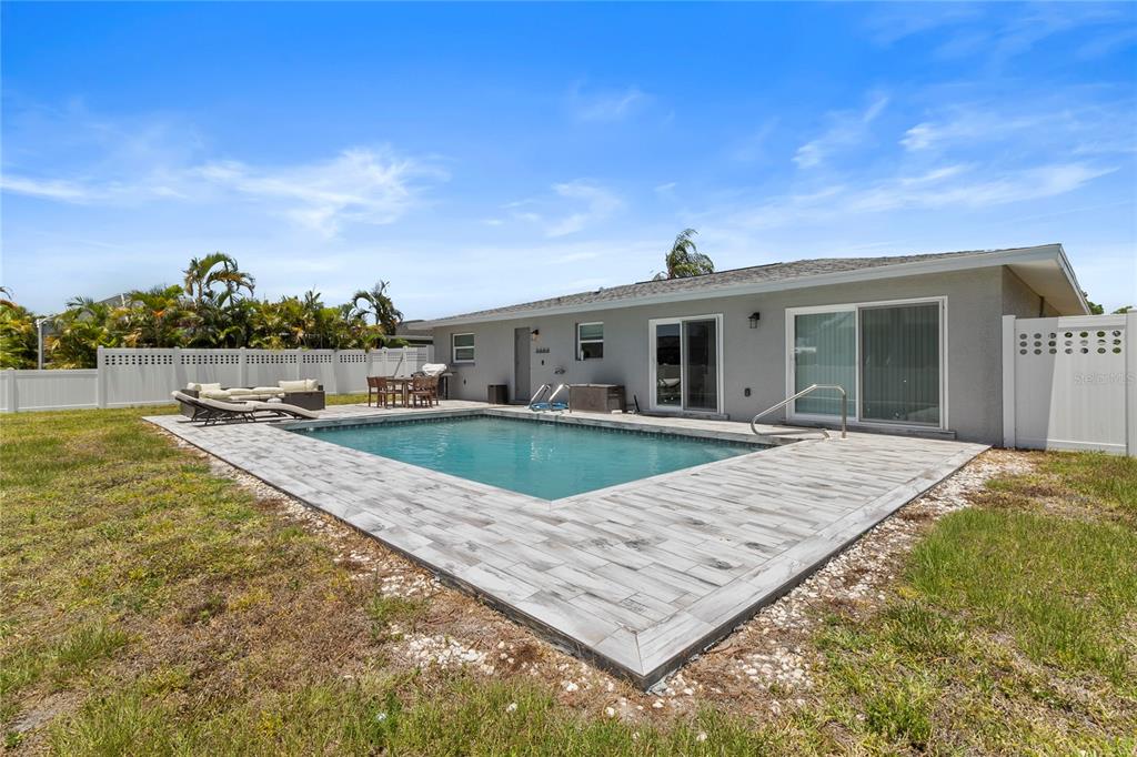 A backyard features a rectangular swimming pool with a light-colored tiled patio and white fencing — 60 GOLFVIEW ROAD, ROTONDA WEST, FL
