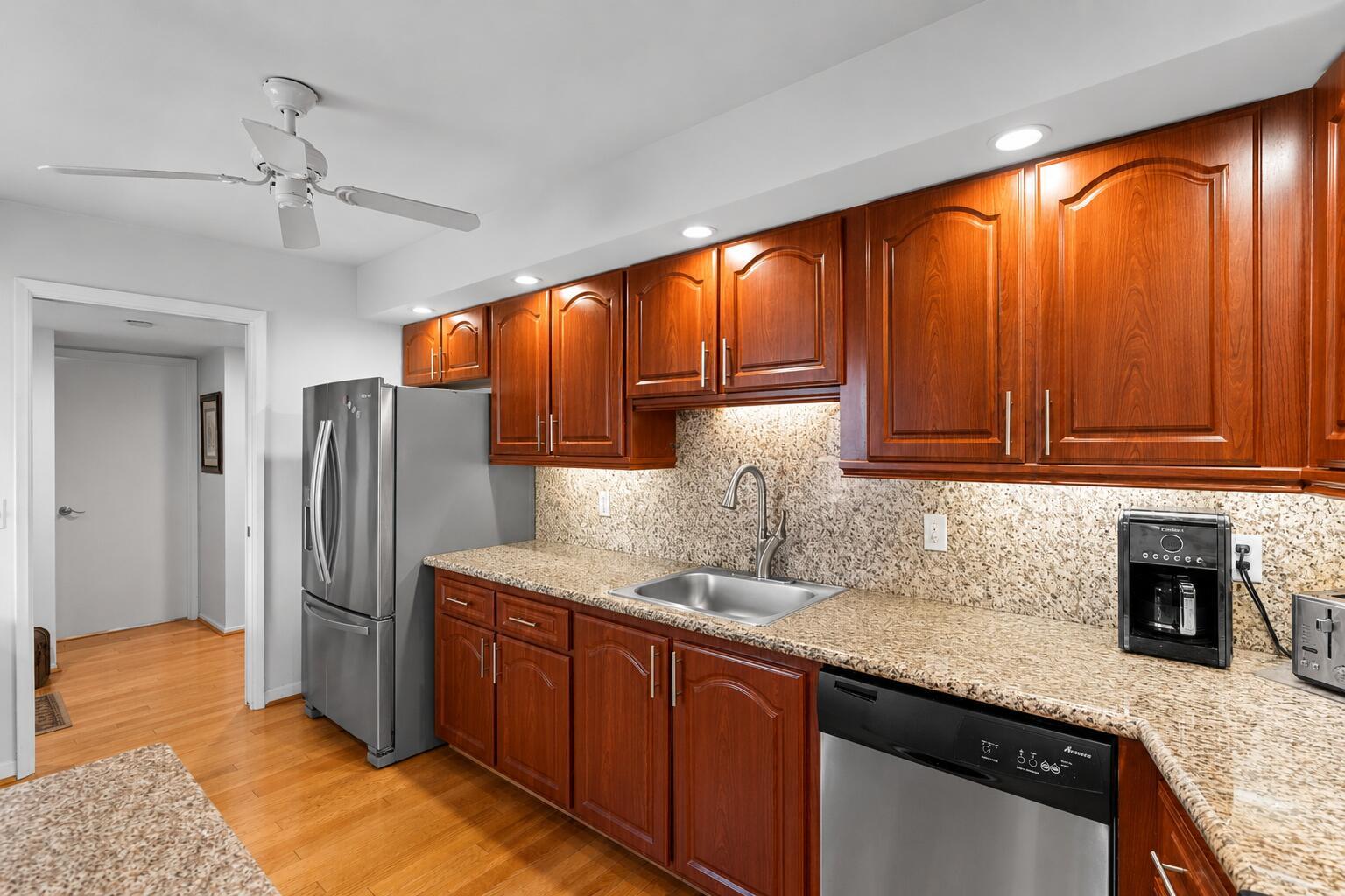 A kitchen features wood cabinets, granite countertops, stainless steel appliances, and a ceiling fan — 625 Oaks Drive # 405, Pompano Beach FL 33069, POMPANO BEACH, FL