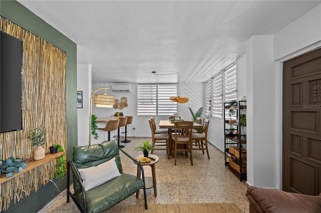 A living and dining area features a green accent wall, bamboo paneling, and terrazzo flooring — 211 CALLE TAPIA, SAN JUAN, PR
