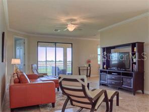 A living room features a leather sofa, an armchair, and a dark wood entertainment center — 7112 GRAND ESTUARY TRAIL UNIT 103, BRADENTON, FL