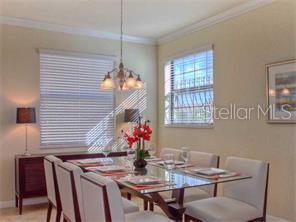 A dining room features a glass-topped table, six upholstered chairs, and a hanging light fixture — 7112 GRAND ESTUARY TRAIL UNIT 103, BRADENTON, FL