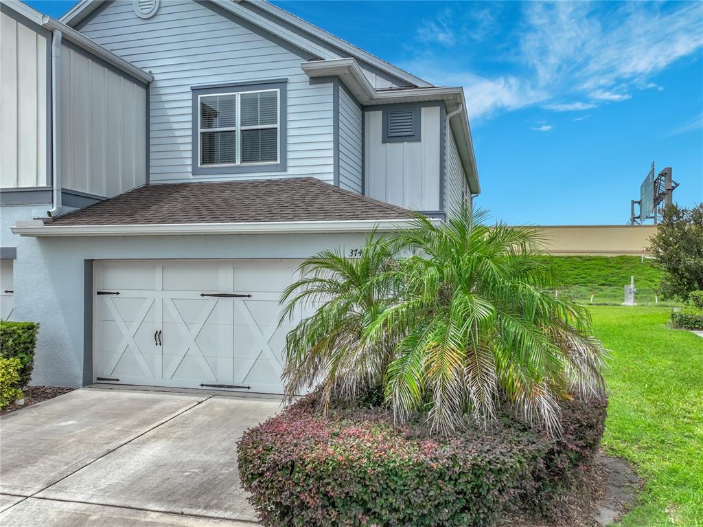 A light blue two-story townhouse with a white garage door and a large palm tree — 3743 PLAINVIEW DRIVE, ORLANDO, FL