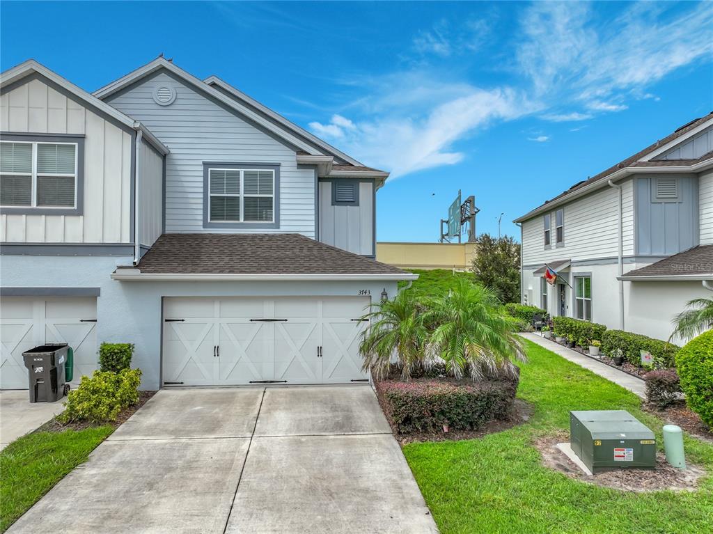 A two-story townhouse with a white garage door, light blue siding, and a concrete driveway — 3743 PLAINVIEW DRIVE, ORLANDO, FL