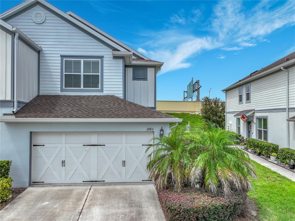 A two-story light blue house features a white garage door and a small palm tree — 3743 PLAINVIEW DRIVE, ORLANDO, FL