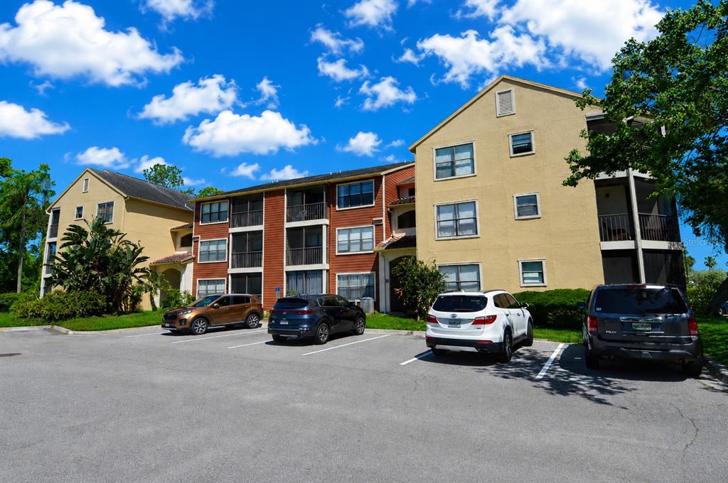 A multi-story apartment building with a parking lot in the foreground under a blue sky — 11901 4TH STREET N UNIT 7204, ST PETERSBURG, FL