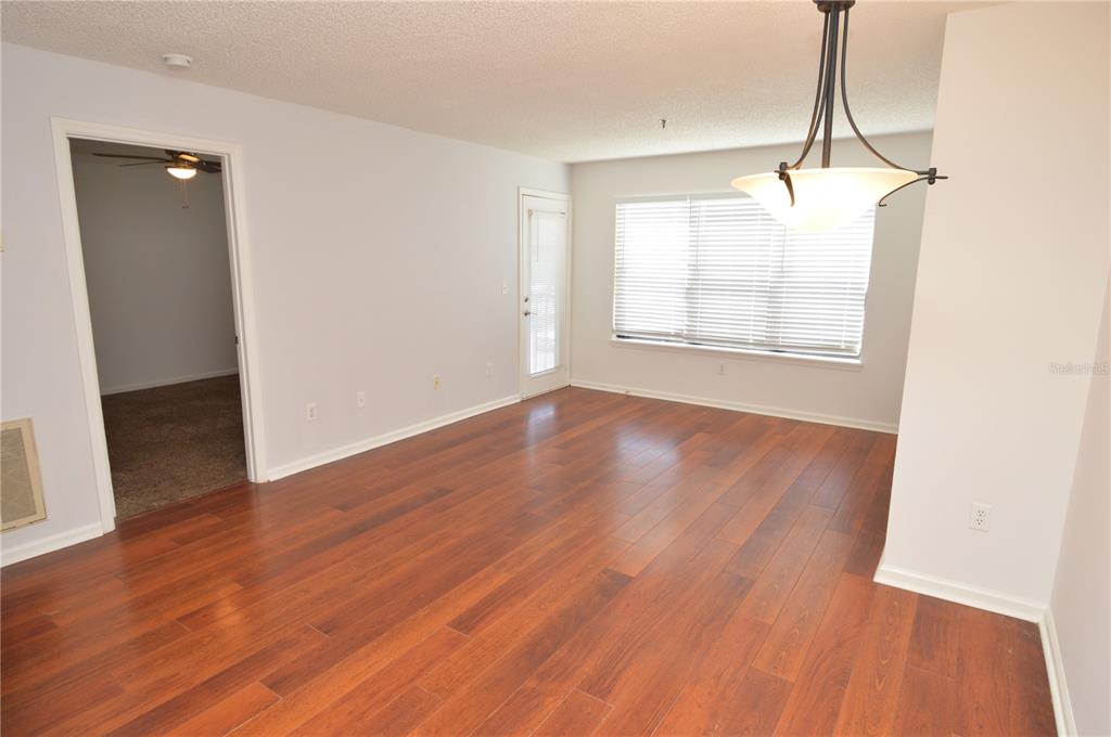 An empty room with wood-look flooring, a ceiling light fixture, and a glass door — 11901 4TH STREET N UNIT 7204, ST PETERSBURG, FL