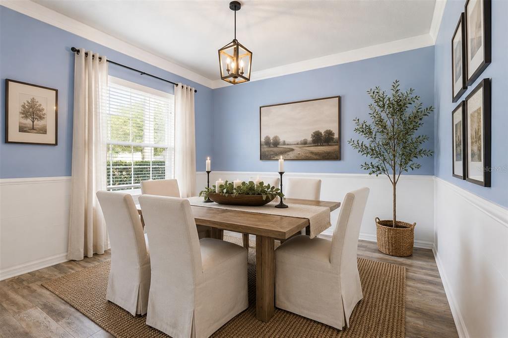 A dining room features light blue walls, white wainscoting, a wooden table, and upholstered chairs — 12549 HAMMOCK POINTE CIRCLE, CLERMONT, FL