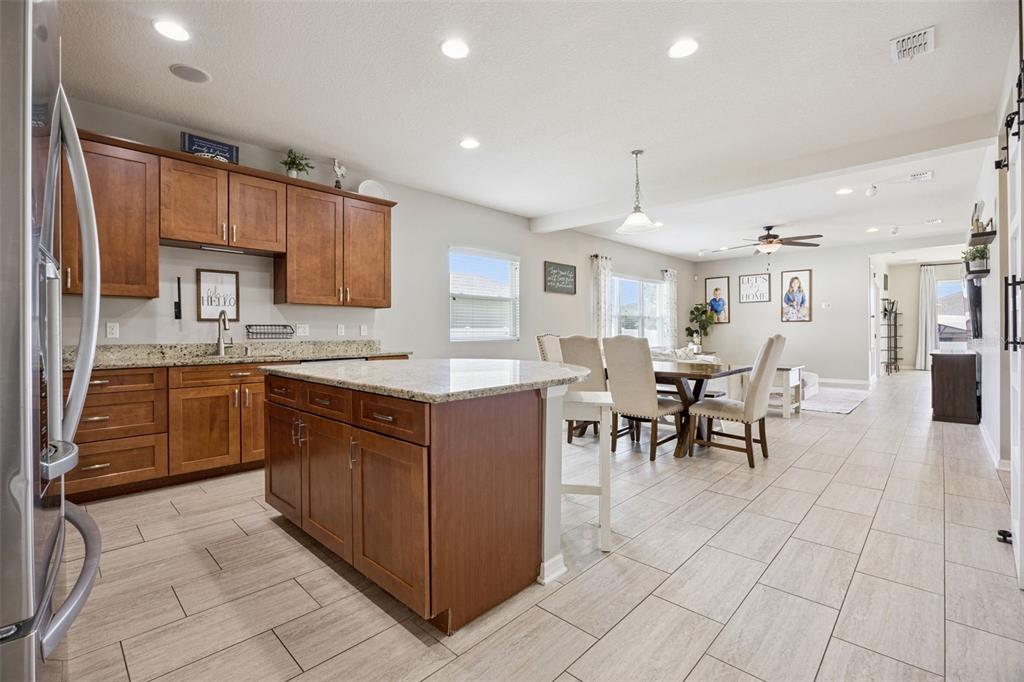 A kitchen with wood cabinets and granite countertops opens into a dining and living area — 12549 HAMMOCK POINTE CIRCLE, CLERMONT, FL