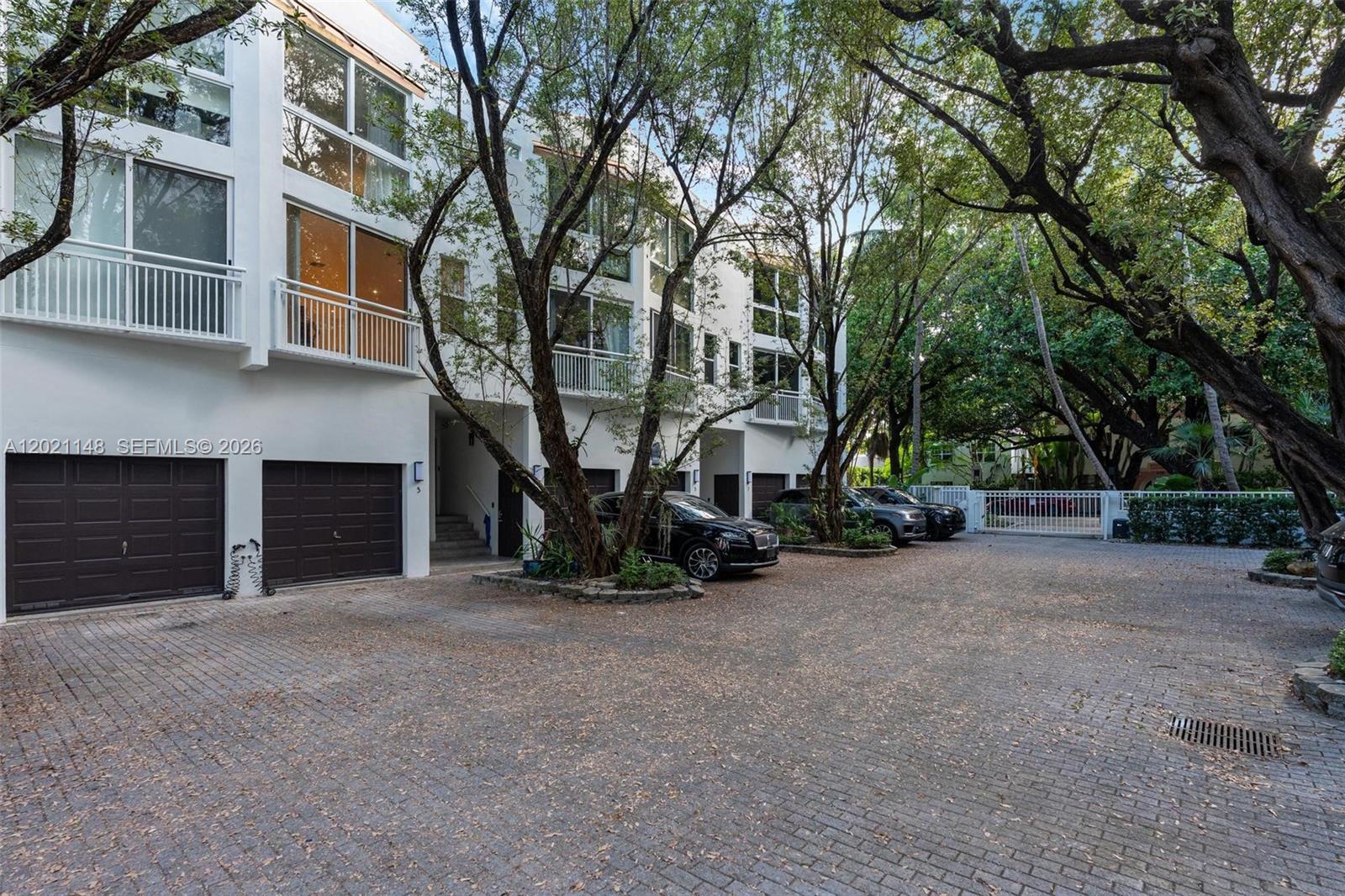 A multi-story white townhouse complex features a paved driveway, garage doors, and mature trees — 325 Meridian Ave # 5, Miami Beach FL 33139, MIAMI BEACH, FL