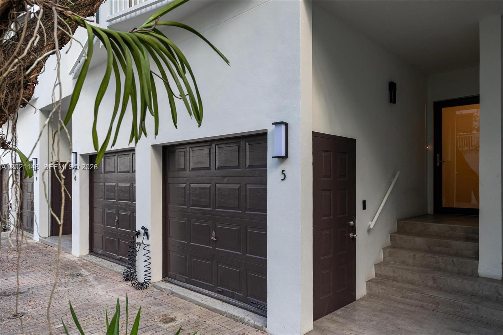 The exterior of a townhouse features two brown garage doors and a front entrance staircase — 325 Meridian Ave # 5, Miami Beach FL 33139, MIAMI BEACH, FL