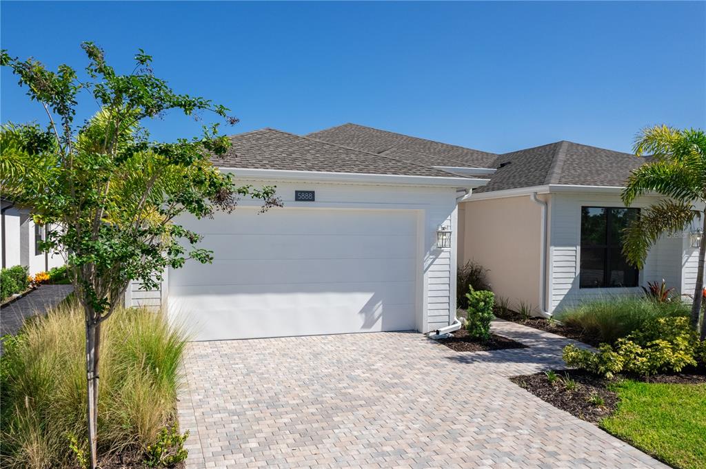 A single-story house with a white garage door, paved driveway, and landscaped front yard — 5888 WINDBREAK COURT, APOLLO BEACH, FL