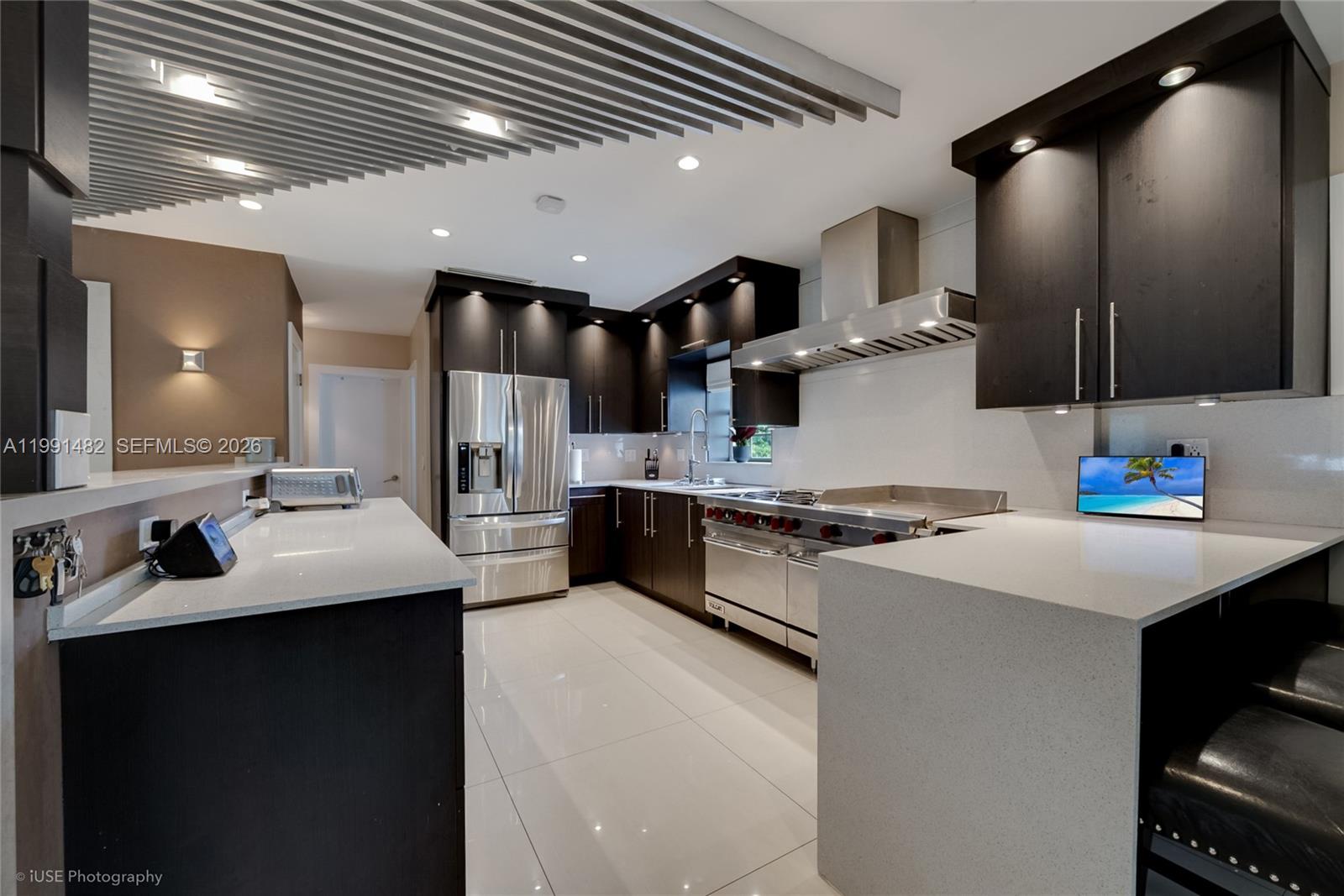 A modern kitchen features dark cabinetry, stainless steel appliances, and white quartz countertops — 7940 SW 20th Street, Miami FL 33155, MIAMI, FL