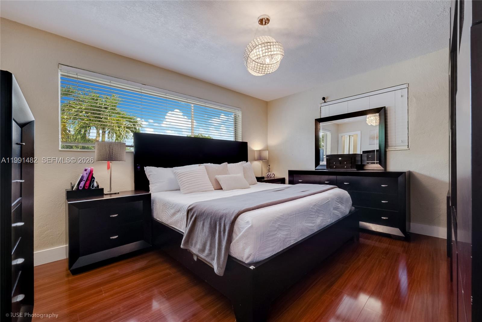 A bedroom features a black bed frame, matching furniture, hardwood floors, and a large window — 7940 SW 20th Street, Miami FL 33155, MIAMI, FL