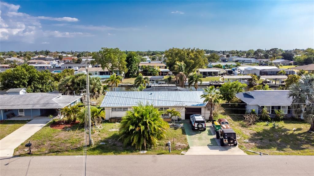 An aerial view shows a single-story house with a metal roof and a driveway — 117 BEDFORD DRIVE NE, PORT CHARLOTTE, FL