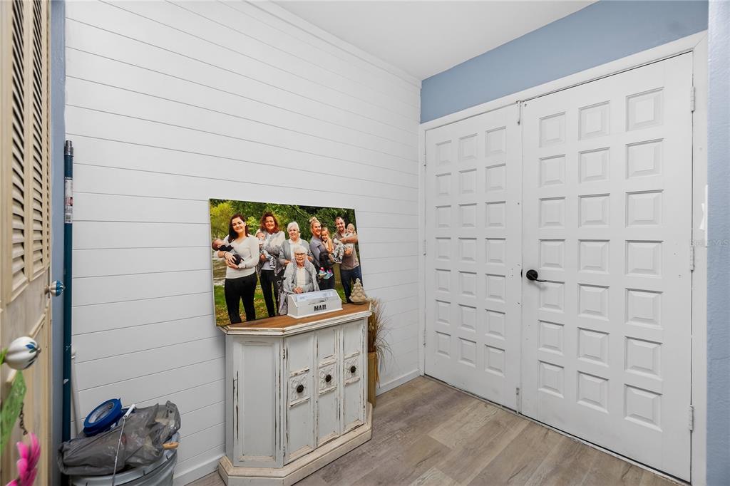 An entryway features white shiplap walls, a wooden cabinet, a family photo, and double doors — 117 BEDFORD DRIVE NE, PORT CHARLOTTE, FL