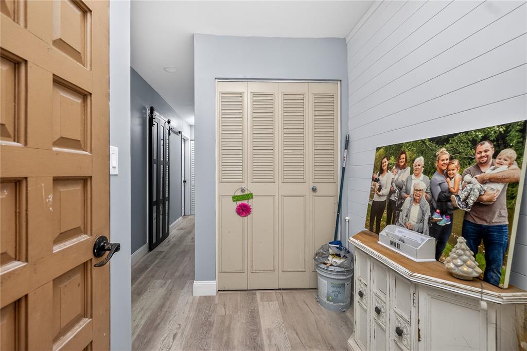 An entryway features a wood door, light wood-look flooring, a closet, and a white cabinet — 117 BEDFORD DRIVE NE, PORT CHARLOTTE, FL