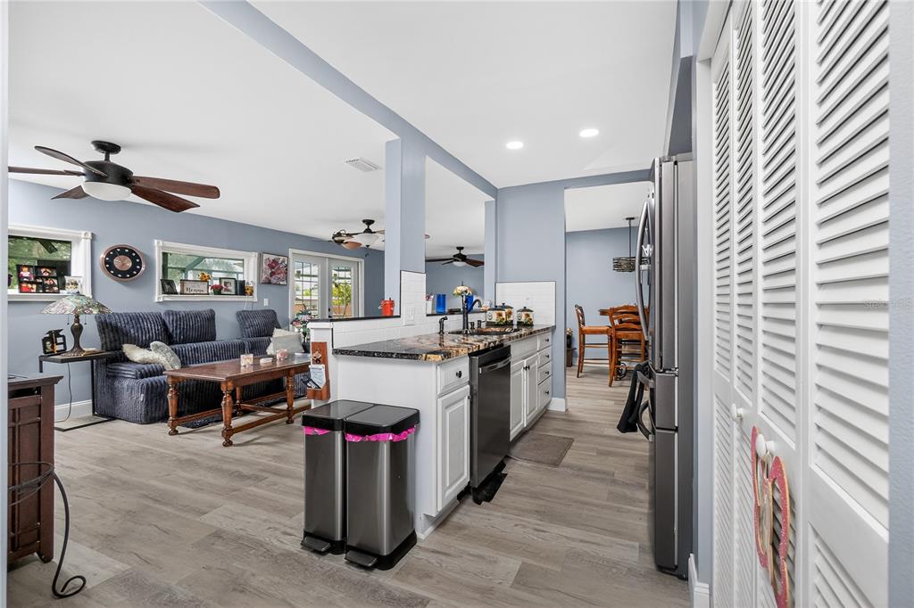 A kitchen with white cabinets and granite countertops opens into a living room with blue walls — 117 BEDFORD DRIVE NE, PORT CHARLOTTE, FL