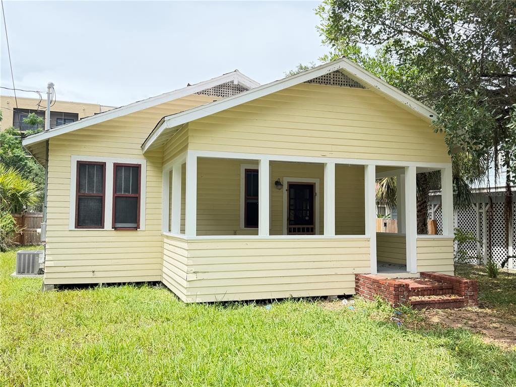 A yellow house with horizontal siding features a front porch and brick steps — 1555 7TH STREET, SARASOTA, FL
