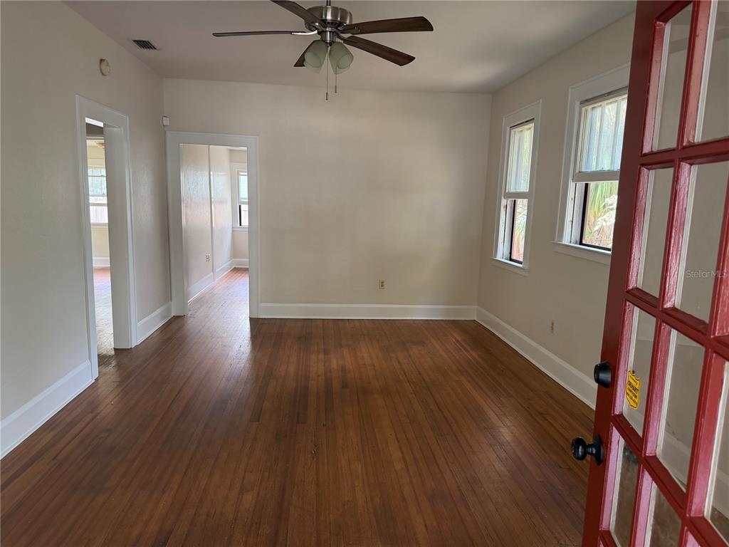 An interior view of a living room with hardwood floors, a ceiling fan, and windows — 1555 7TH STREET, SARASOTA, FL
