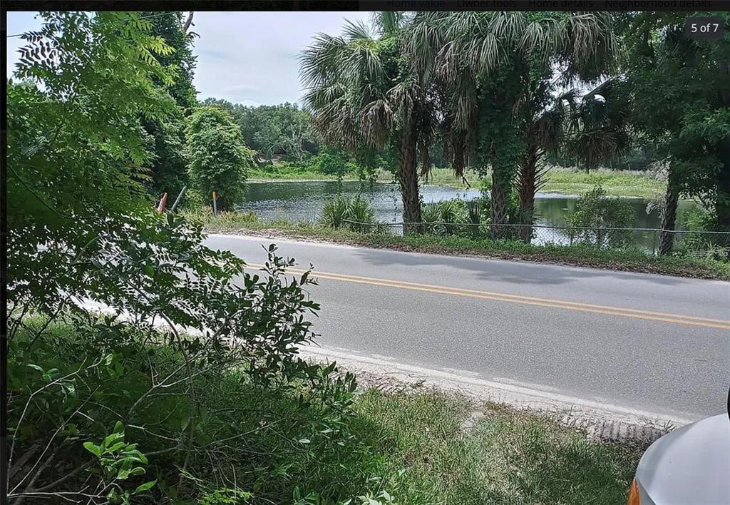A paved road runs alongside a small lake surrounded by trees and palm trees — 438 HUNTINGTON SHORTCUT ROAD, POMONA PARK, FL
