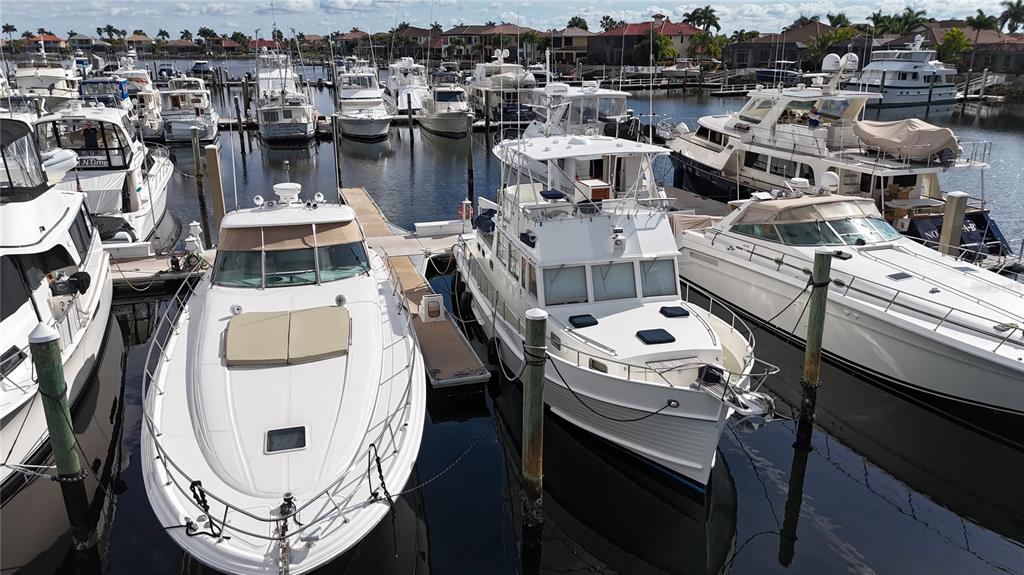 Several white motor yachts are docked in a marina with houses visible in the background — 102 RIVIERA DUNES WAY UNIT S-54, PALMETTO, FL