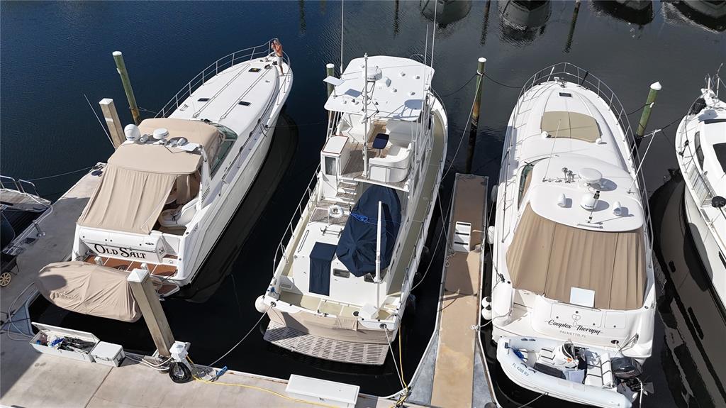 An aerial view shows three white yachts docked side-by-side in a marina — 102 RIVIERA DUNES WAY UNIT S-54, PALMETTO, FL