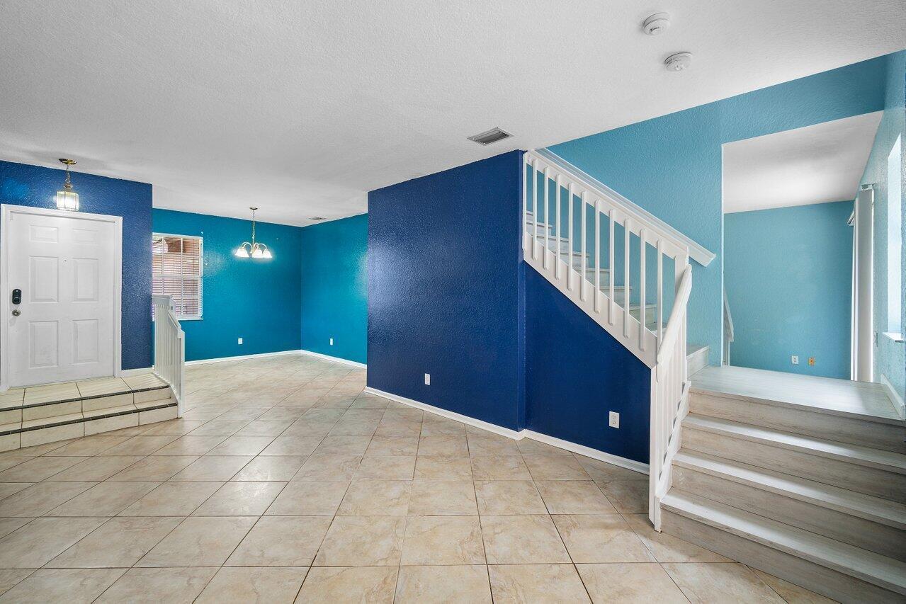 An entryway with tiled floors, blue walls, and a staircase leading to an upper level — 5453 Queenship Court, FL 33463, FL