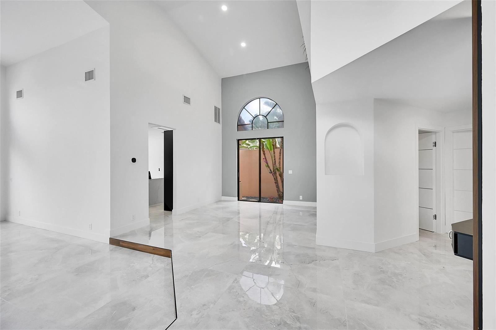 A bright, high-ceilinged living room features white walls, gray marble flooring, and an arched window — 6488 Via Rosa, Boca Raton FL 33433, BOCA RATON, FL