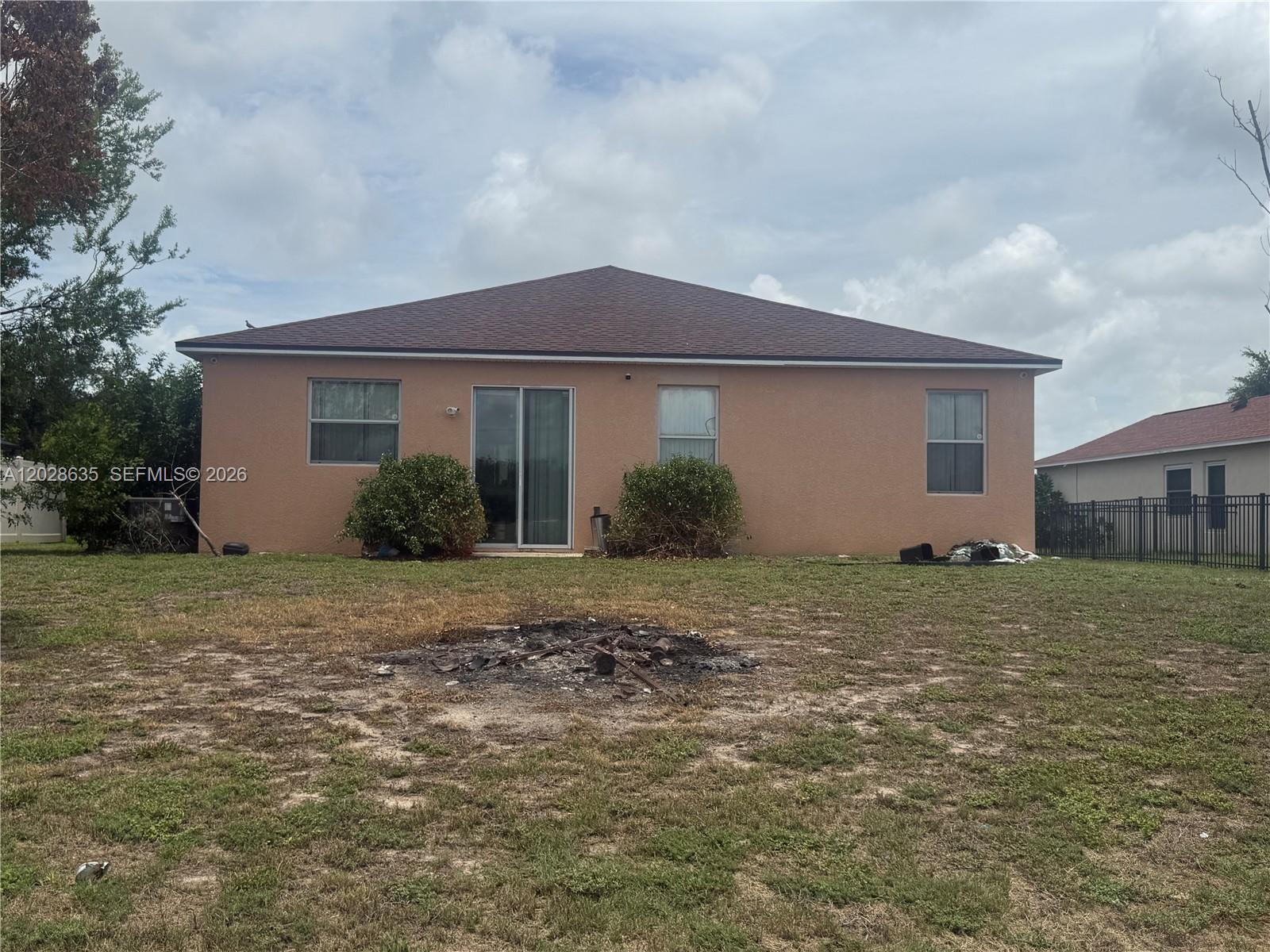 The rear exterior of a single-story stucco house features a sliding glass door and yard — 342 STAR SHELL DR, Tampa FL 33572, TAMPA, FL