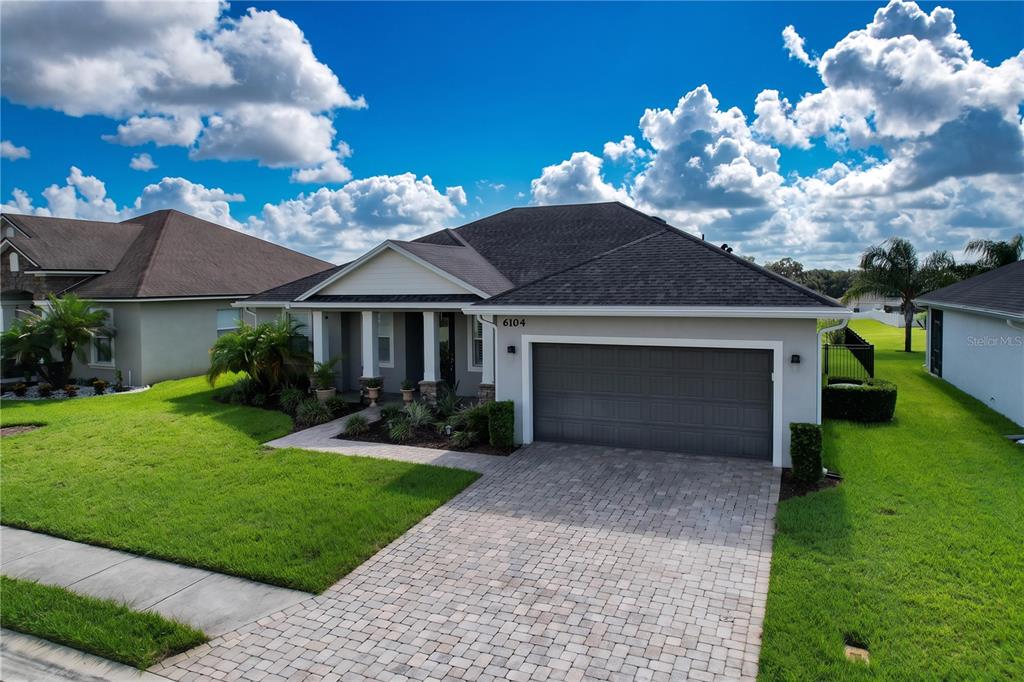 A single-story house with a gray garage, a paved driveway, and a covered front porch — 6104 HIGHLANDS GRACE BOULEVARD, LAKELAND, FL