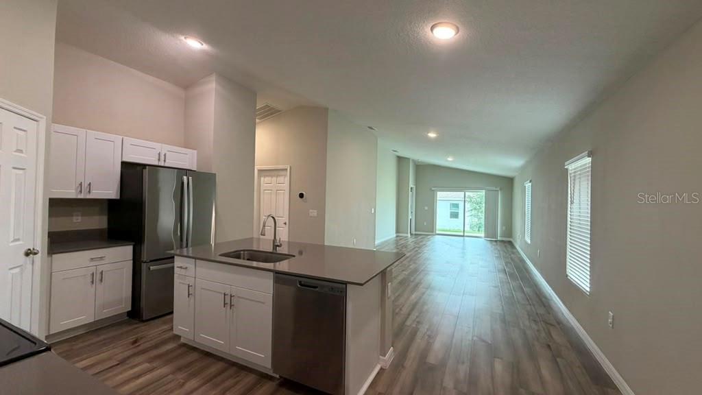 A kitchen with white cabinets and a stainless steel island overlooks an open living area — 4904 MAINSAIL STREET, HAINES CITY, FL