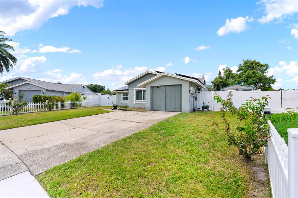 A single-story house with a gray exterior, solar panels, and a concrete driveway — 6415 MONTEREY BOULEVARD, TAMPA, FL