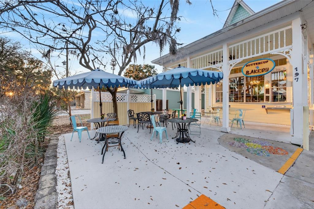 An outdoor patio with tables and umbrellas sits in front of a bakery building — 197 E CHURCH STREET, DELAND, FL