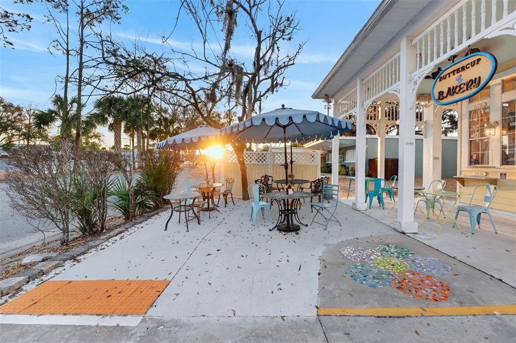 An outdoor patio with tables, chairs, and umbrellas sits in front of a bakery building — 197 E CHURCH STREET, DELAND, FL
