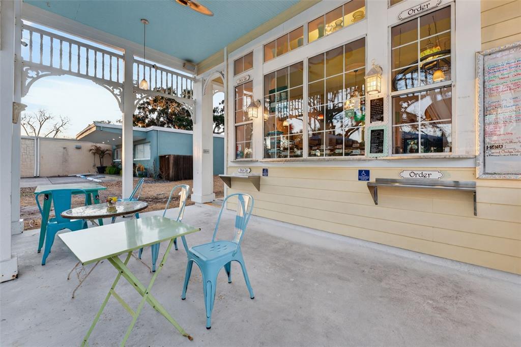 A covered outdoor patio features light blue metal chairs, tables, and a service window for ordering — 197 E CHURCH STREET, DELAND, FL